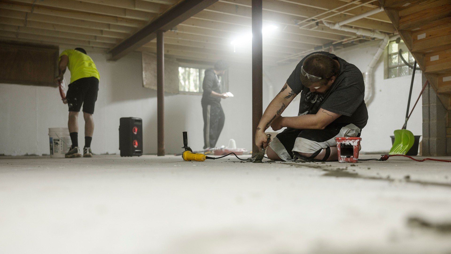 Group of workers doing basement waterproofing. Worker sealing cracks in the basement foor for waterpfoofing.