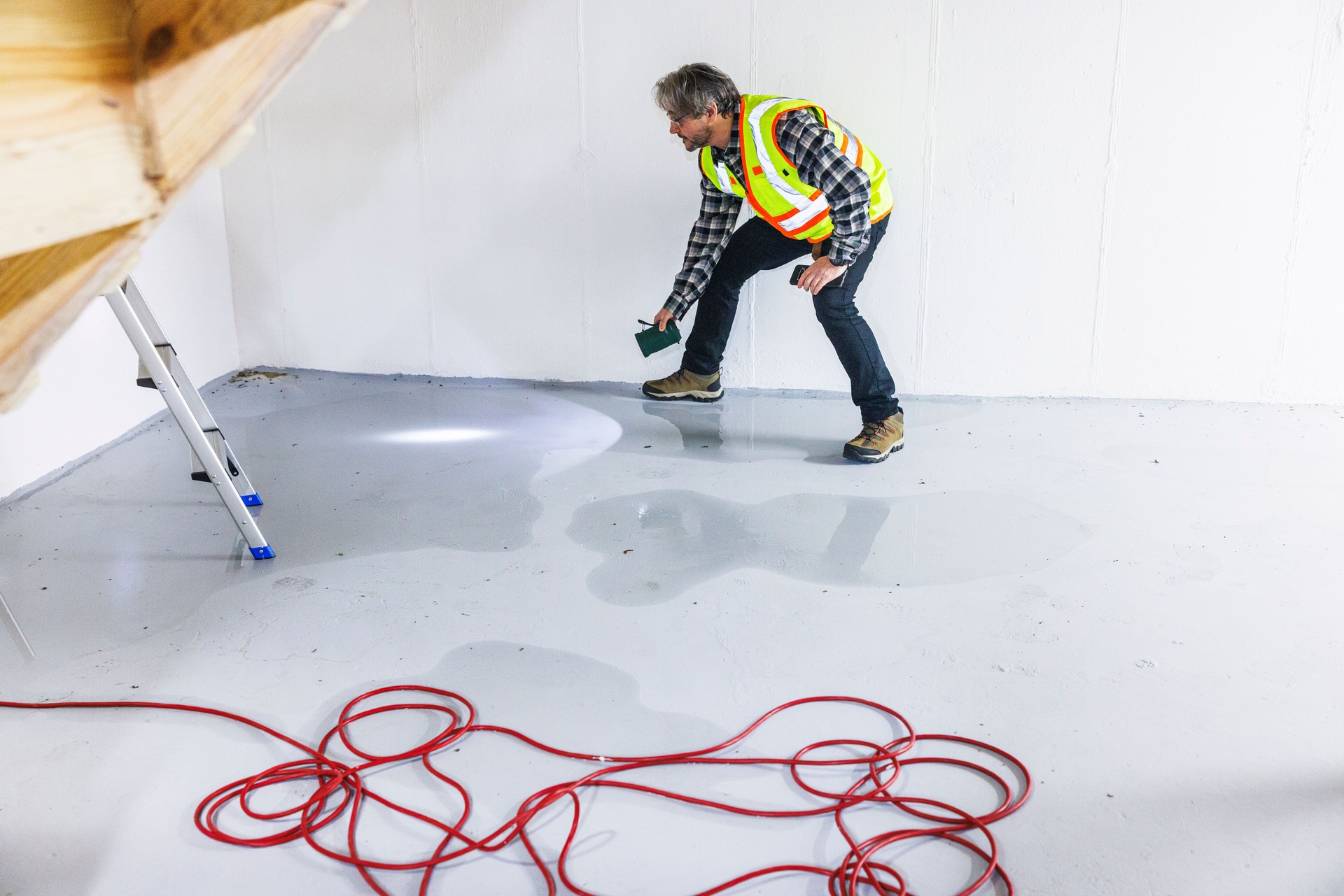 Risk assessment after cellar flooding. A mature adjuster with flashlight, examines flood consequences